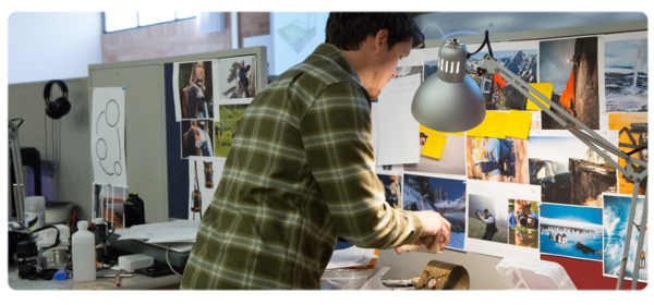 一位产品设计专业的学生在实验室工作站工作，上面覆盖着五颜六色的灵感照片