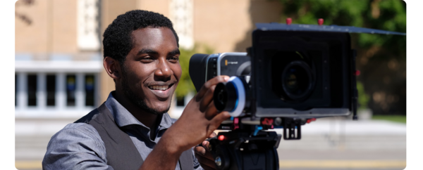 A student films using a film camera.
